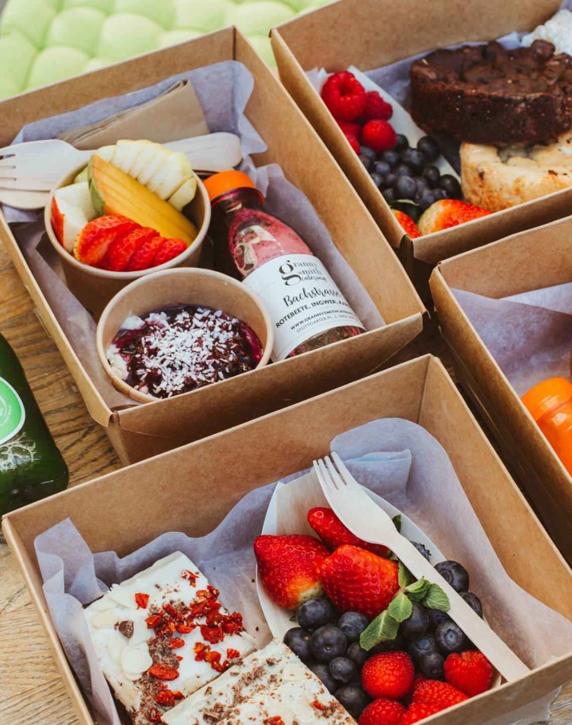Frühstücksboxen mit Obst, Kuchen und Saft